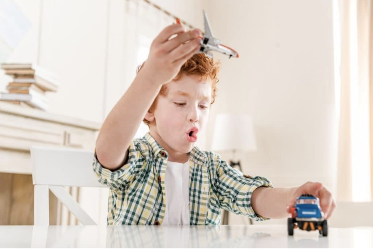 A young boy plays with a toy plane and truck