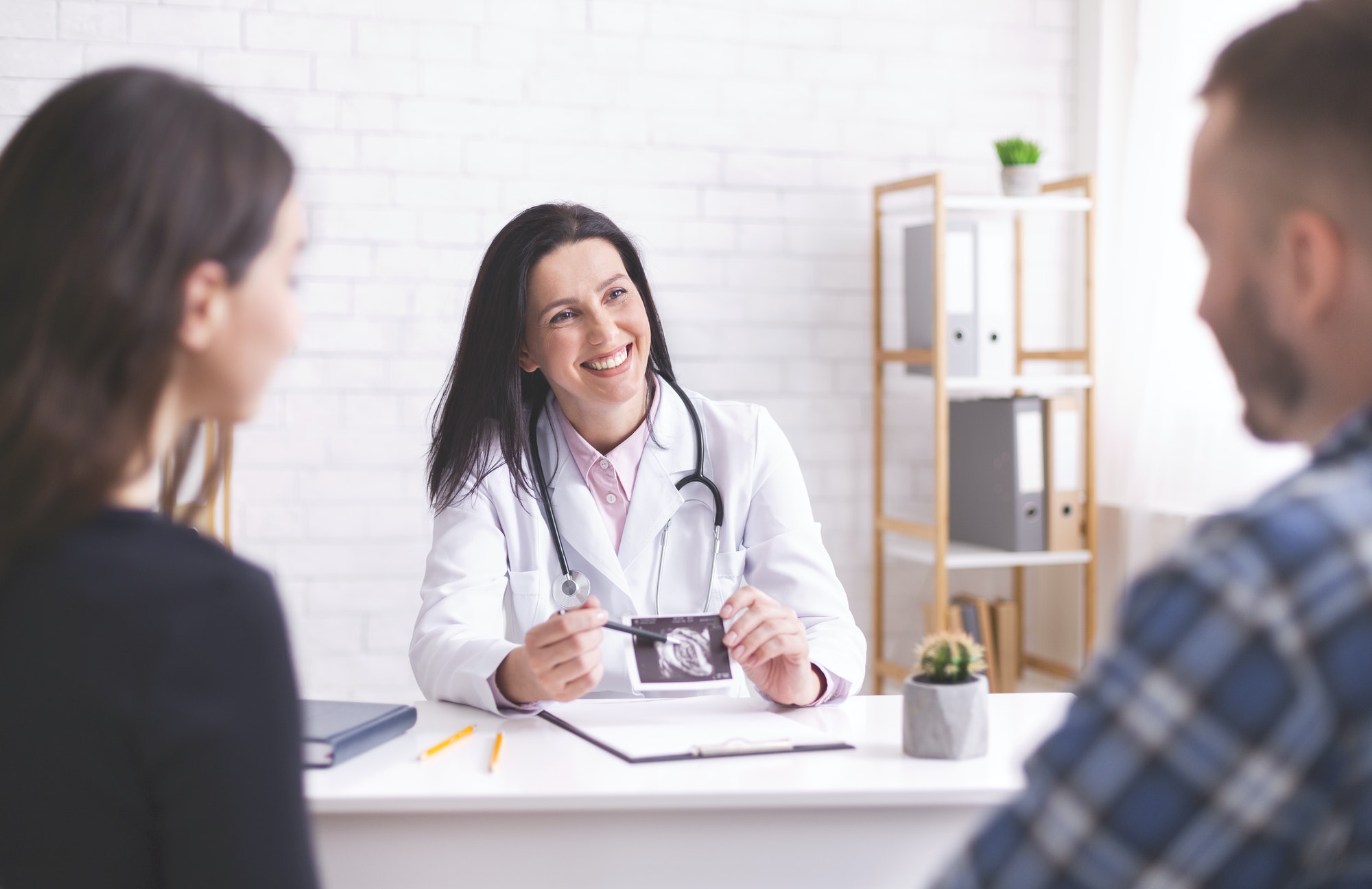 Friendly doctor showing ultrasound picture to young couple