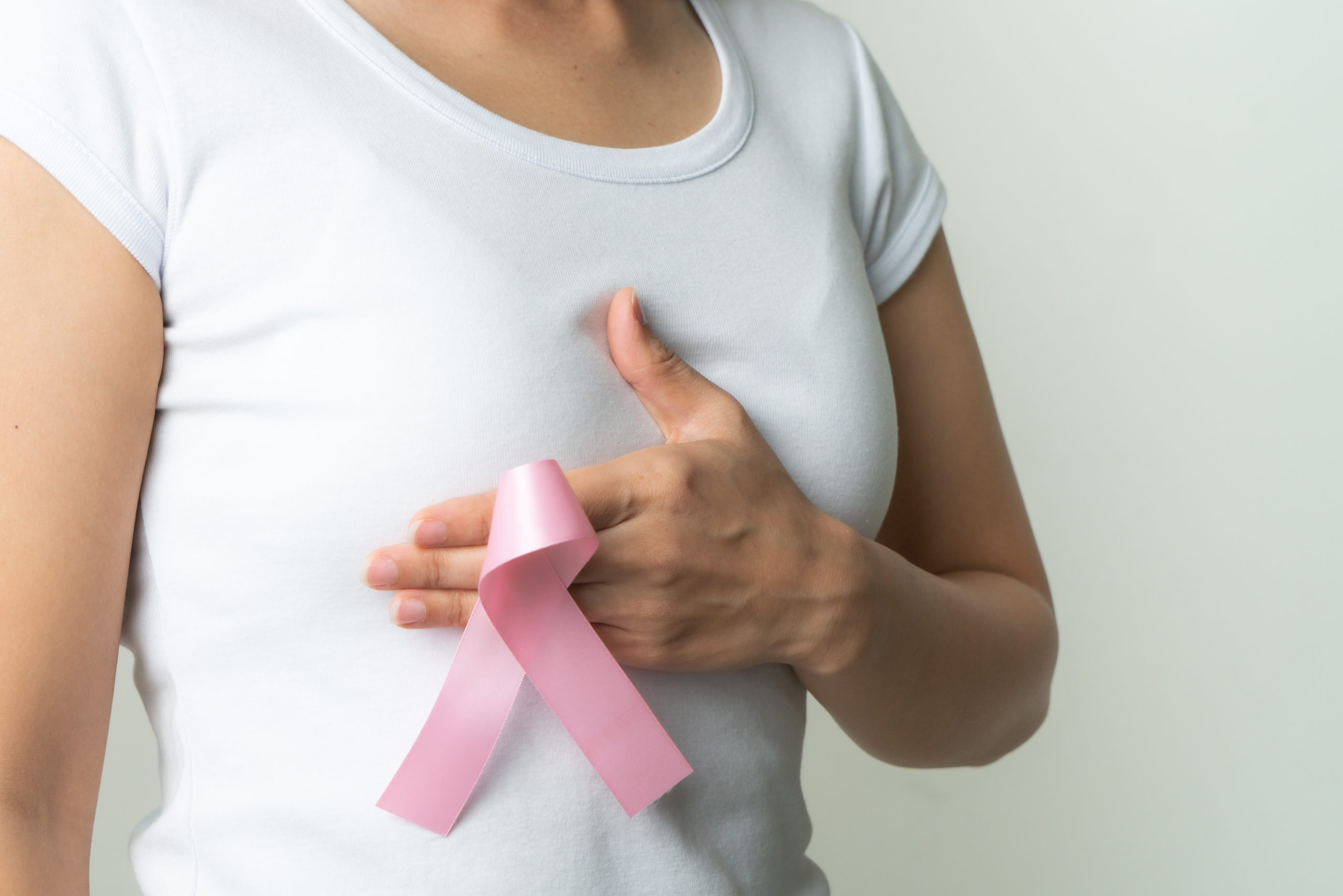 woman holding breast cancer awareness ribbon to her chest