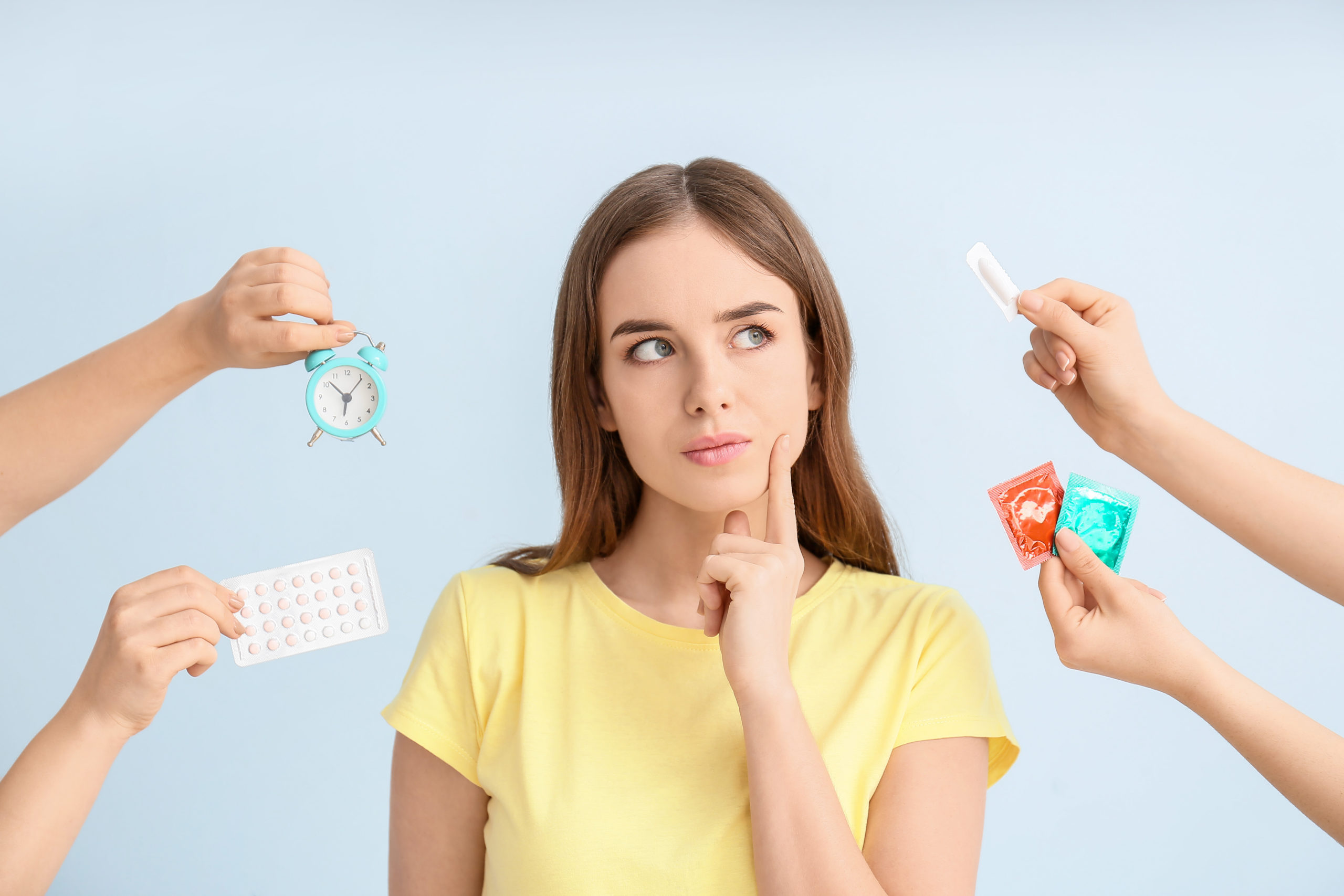 woman surrounded by birth control methods thinking about which to choose